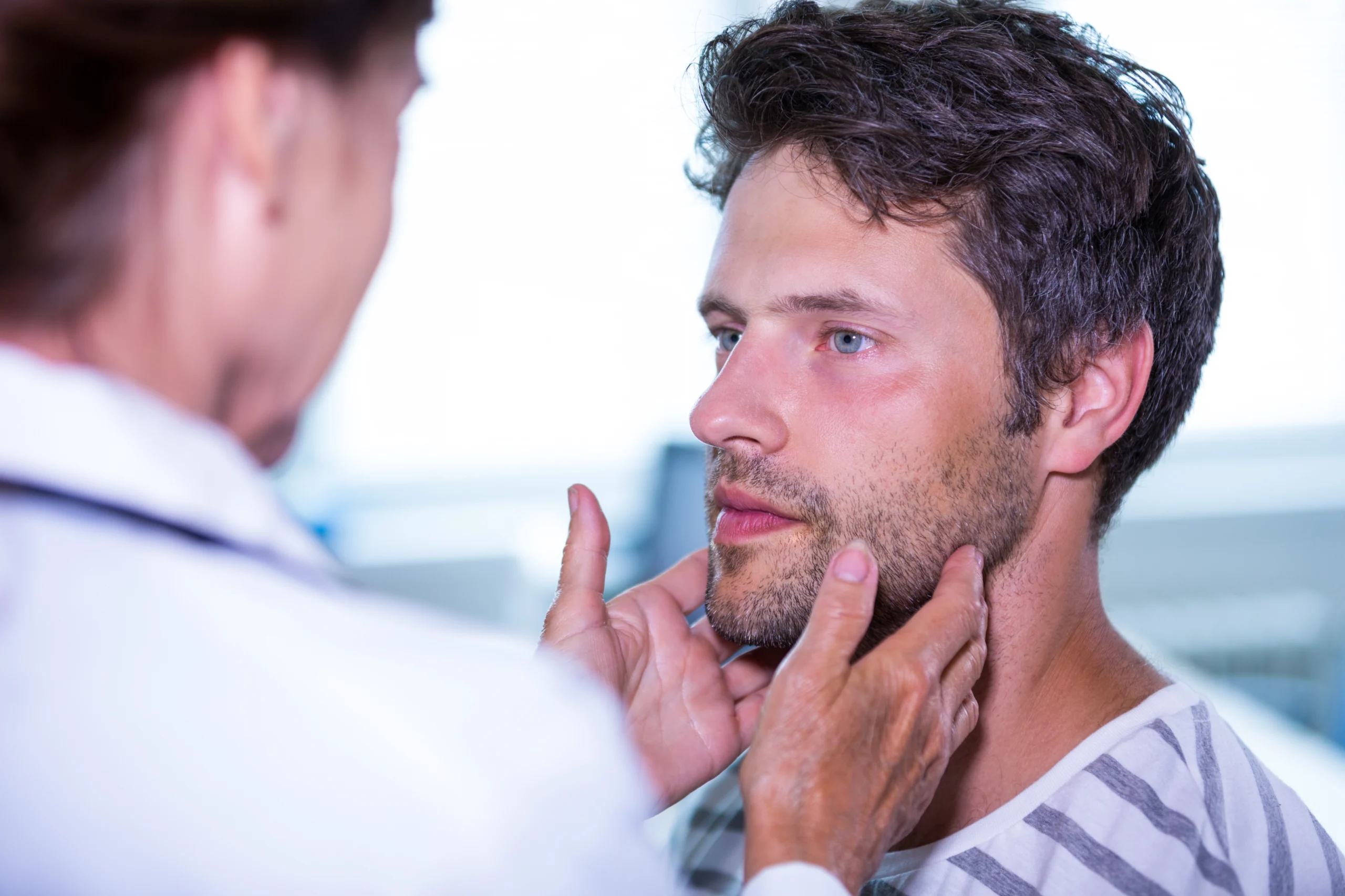 A doctor examining his patient's chin to determine the best chin implant projection size